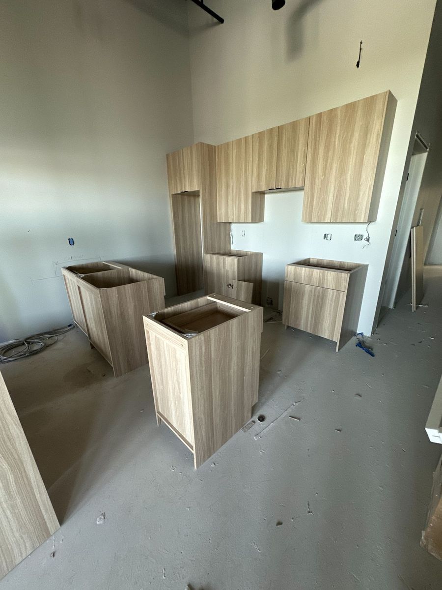 Light oak multifamily kitchen cabinets staged by unit type before countertops