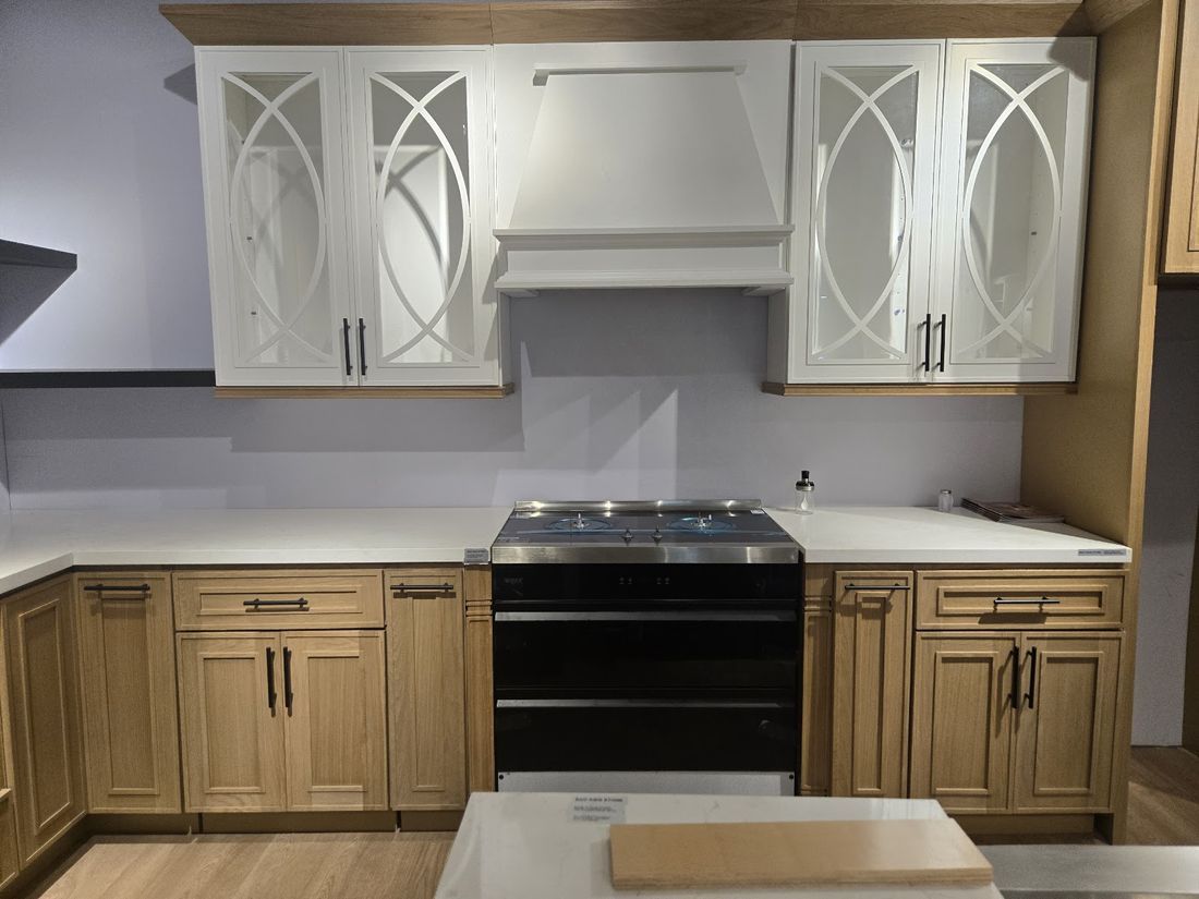 Two-tone apartment kitchen with white uppers, wood base cabinets, and white quartz countertop